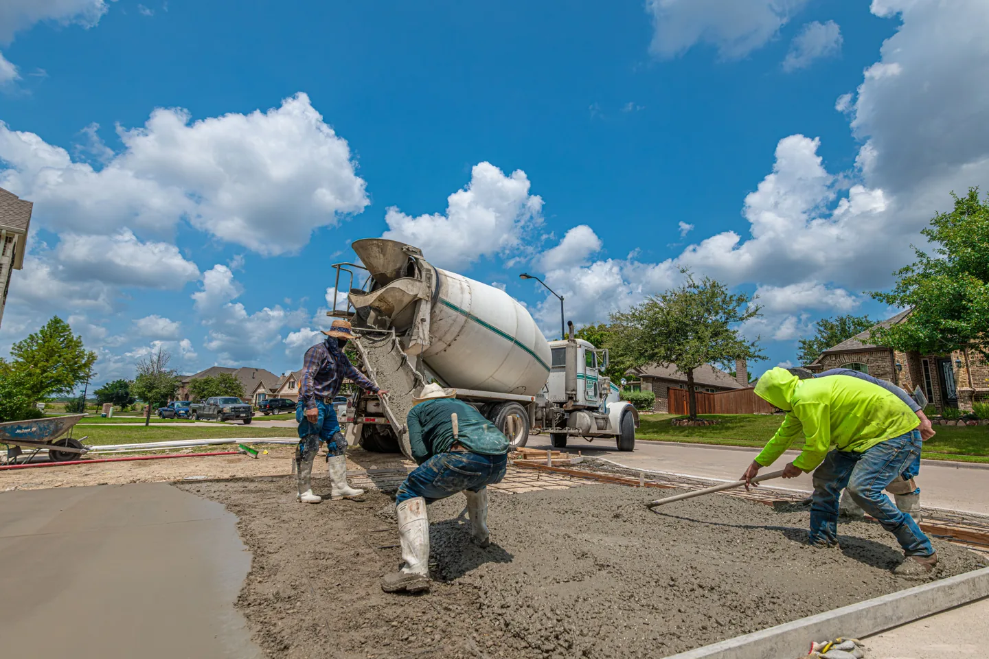 Workers placing concrete beside a residential property, representative installation process
