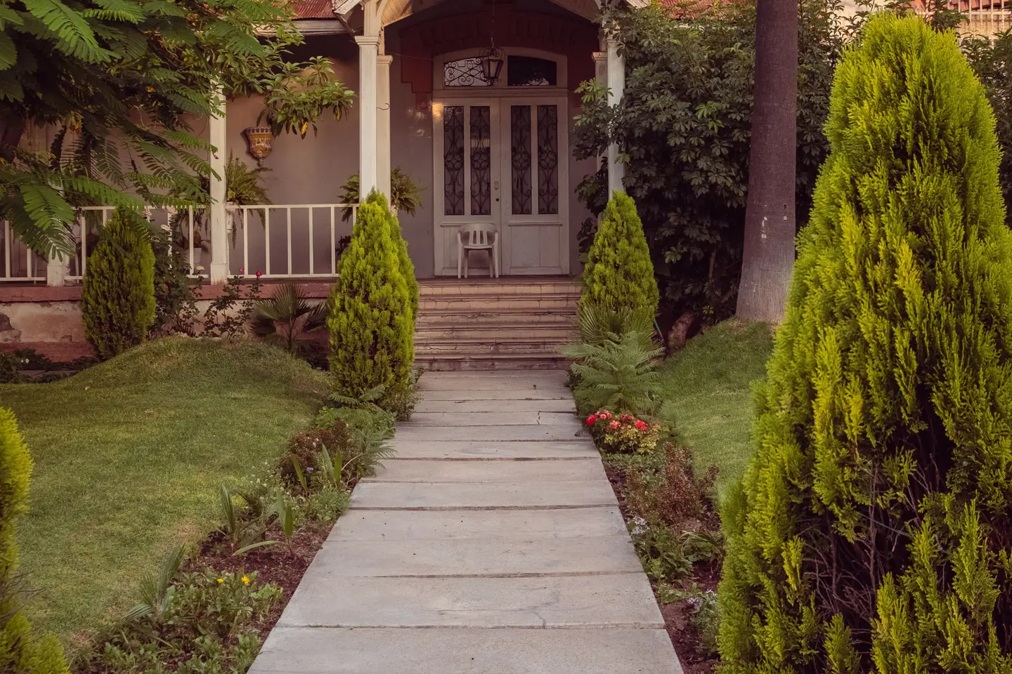 Jointed concrete walkway toward a planted residential porch